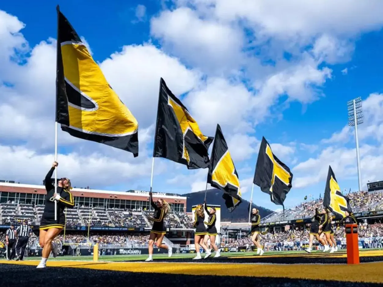 Cheerleaders waving flags on endzone